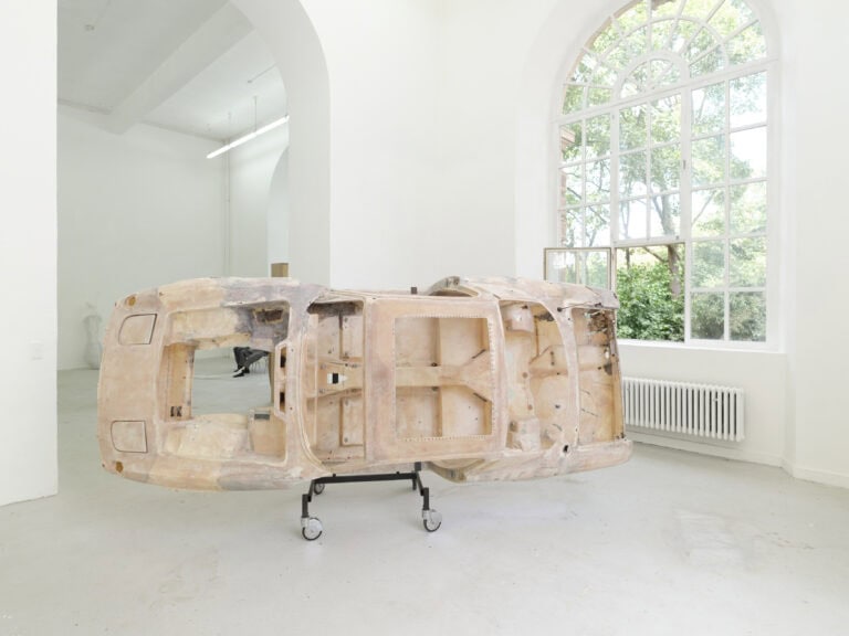 Foto: Skulptur eines Autos auf einem Rollwagen in einem Ausstellungsraum