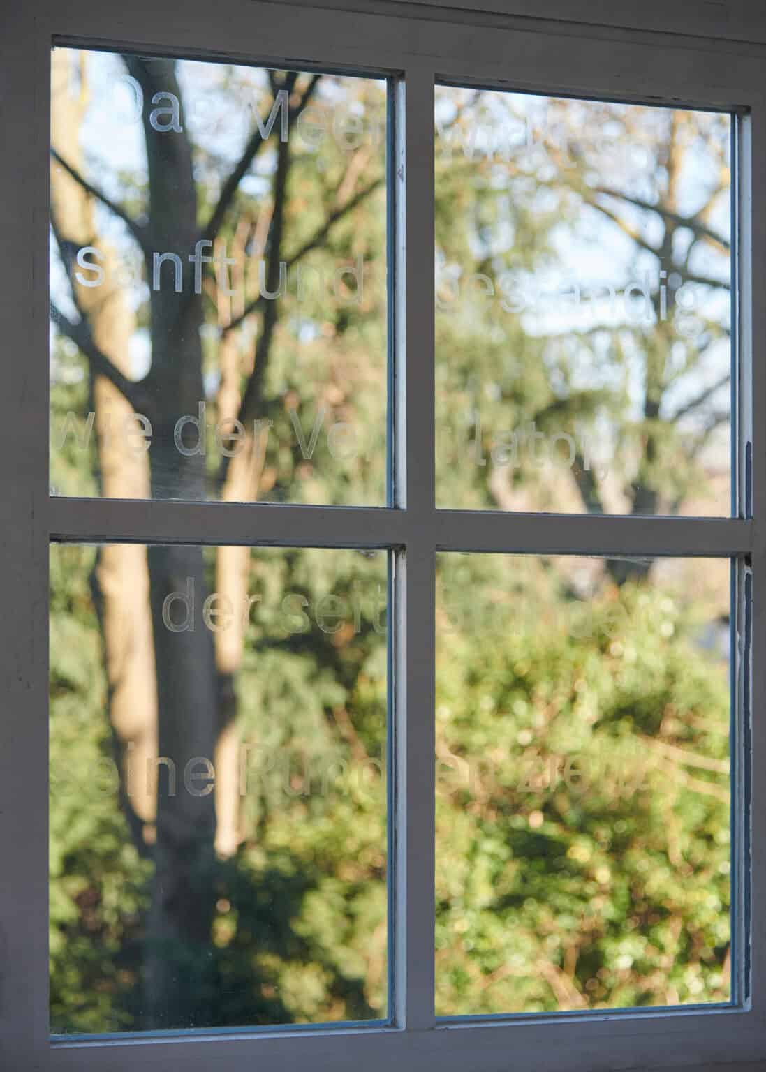 Foto: Nahaufnahme von Fensterscheiben, auf denen ein matter, halbtransparenter Schriftzug zu erkennen ist.