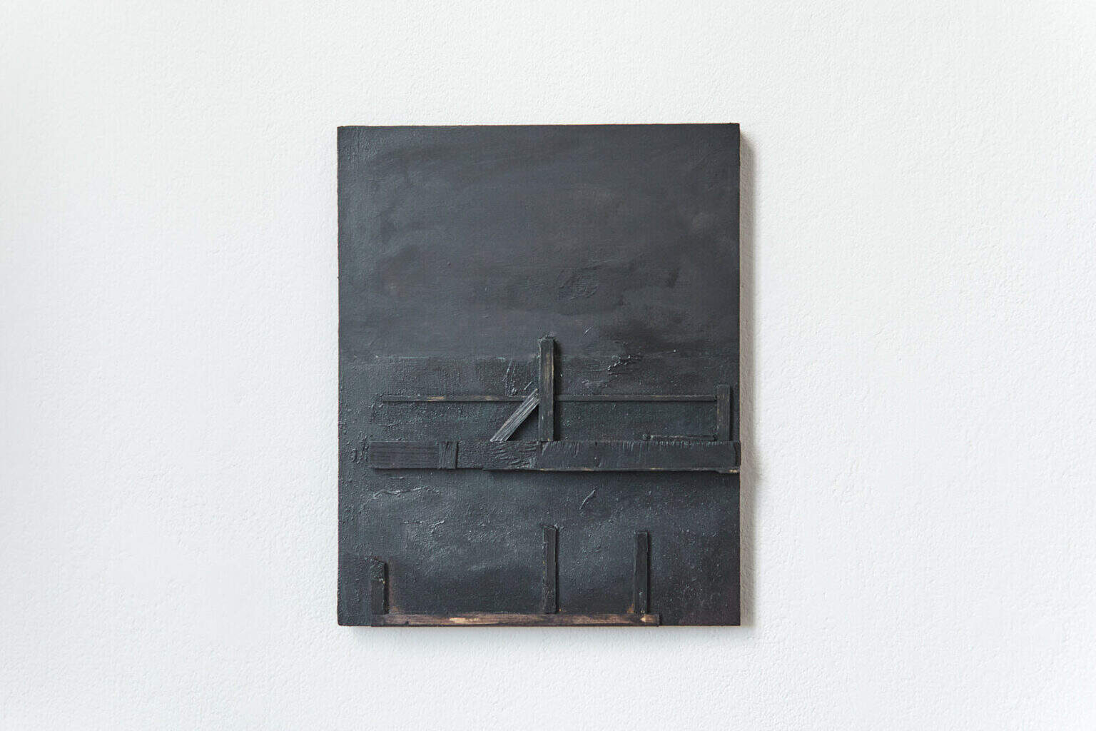 Foto: Ein dunkles, quadratisches Objekt vor weißer Wand.