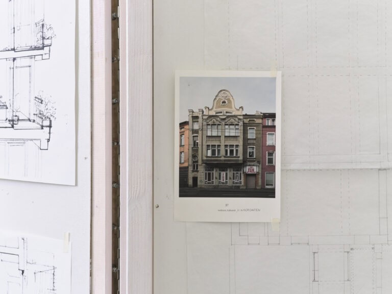 Foto: Detailaufnahme einer Fotografie von einem historischen Gebäude, welches an eine Wand geheftet ist.