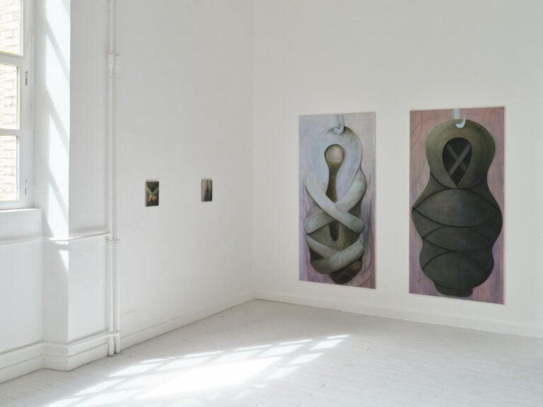 Foto: Aufnahme eines Ausstellungsraums mit weißen Wänden, weißen Dielenboden und Fenster. An der Rückwand sind zwei kleinformatige und zwei großformatige Gemälde zu sehen.