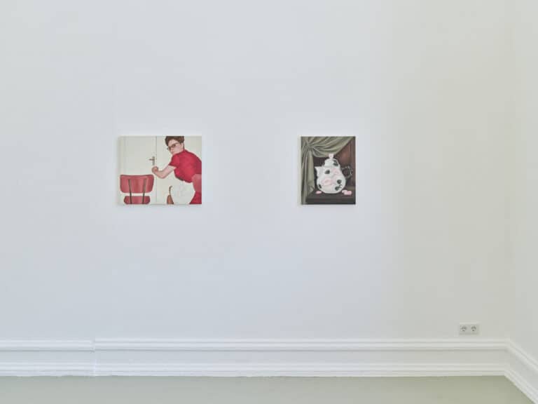 Foto: Aufnahme eines Ausstellungsraums mit weißen Wänden und grauem Boden. An der Wand hängen zwei Gemälde.