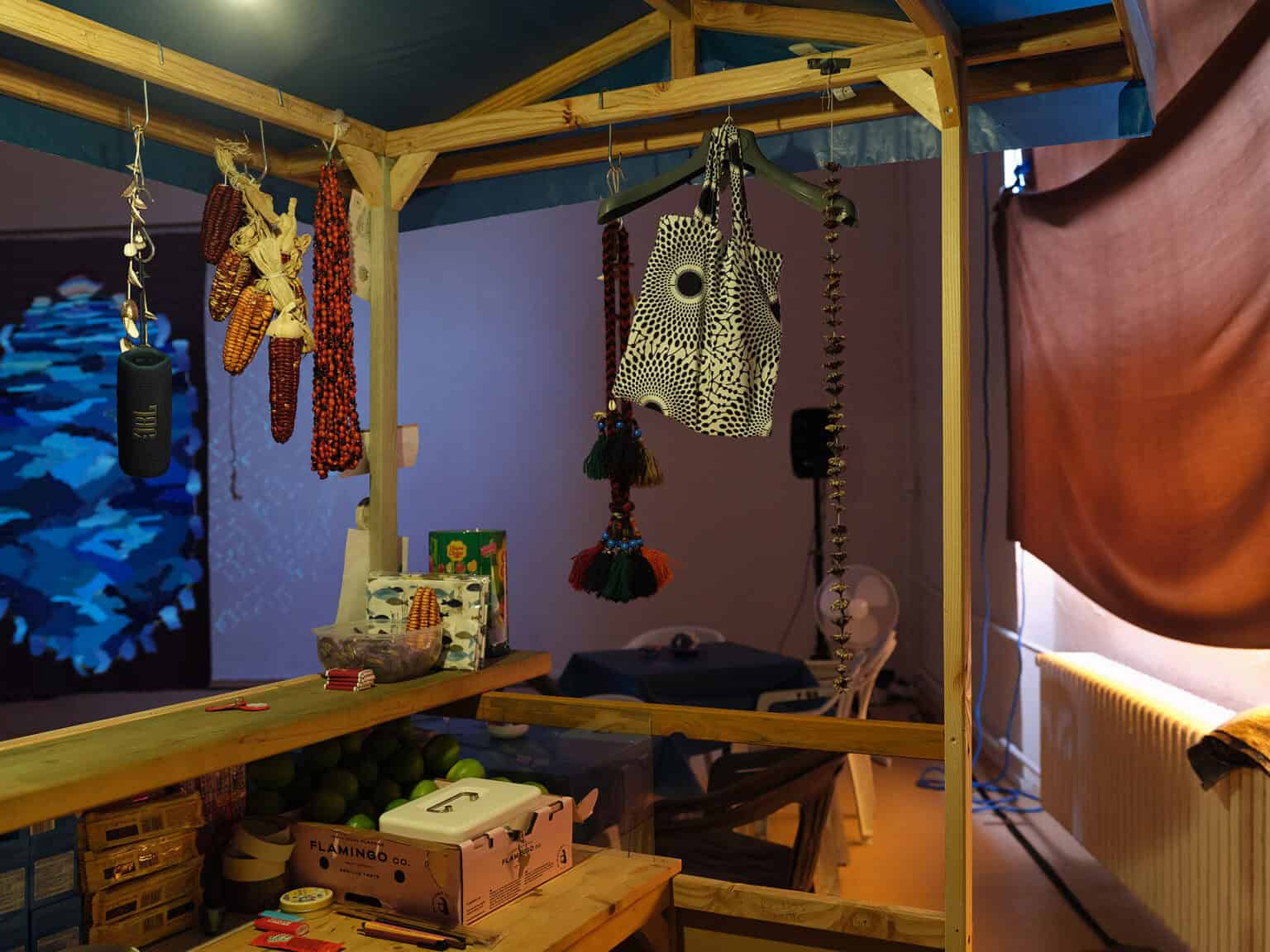Foto: Nahaufnahme einer Holzkonstruktion mit Dach, in der Objekte herunterhängen und auf der Dinge stehen.