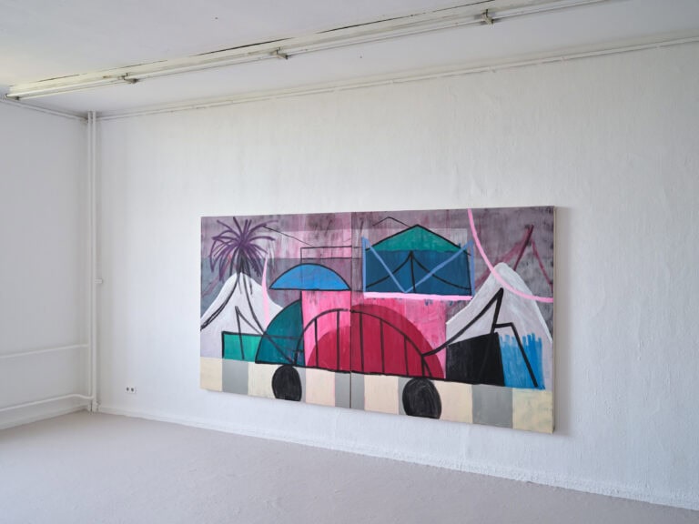 Foto: Aufnahme eines Ausstellungsraums mit weißen Wänden und grauem Boden. An der Wand hängt ein großes abstraktes bunte Gemälde.