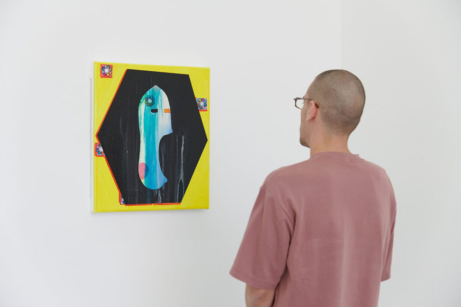 Foto: Eine mittelvormalige Arbeit auf Leinwand vor einer weißen Wand. Davor ein Mensch.