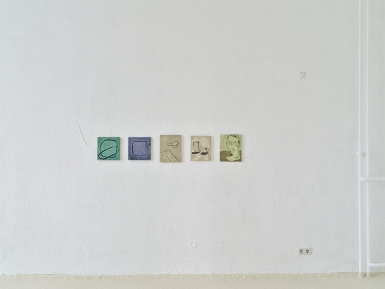 Foto: Detailaufnahme einer weißen Wand mit fünf kleinformatigen Gemälden