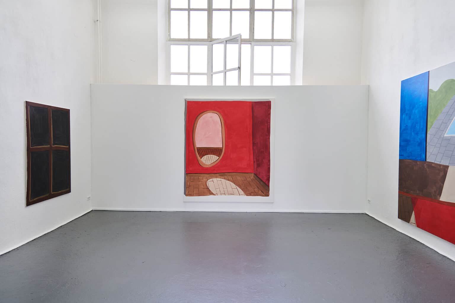 Foto: Ein Raum mit weißen Wänden und grauem Boden. Ein Teil des Fenster ist hinter einer eingezogenen Wand verborgen. An den Wänden hängen großformatige Leinwände.