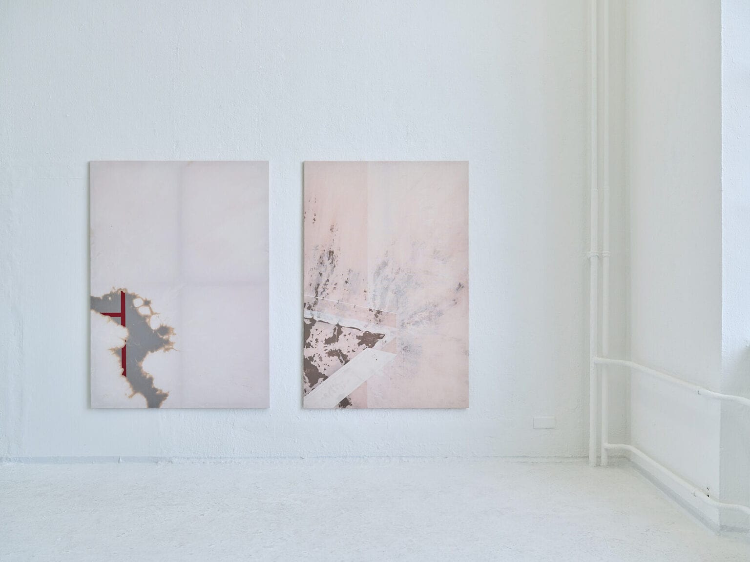 Foto: Ansicht eines Raumes mit weißen Wänden und weißem Boden. An der Wand hängen zwei Leinwandarbeiten im gleichen Format auf gleicher Höhe.