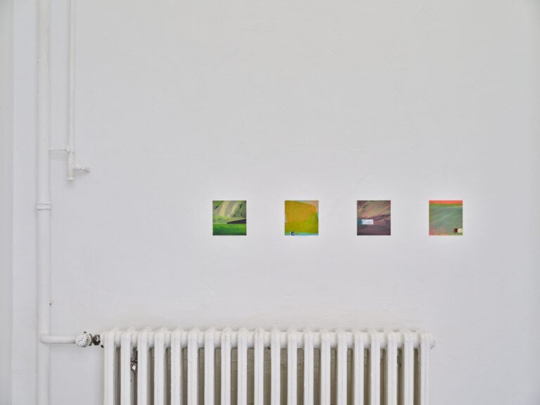 Foto: Aufnahme eines Ausstellungsraums mit weißen Wänden und einem weißen Heizkörper. An den Wänden hängen vier gleich große kleinformatige Bilder.