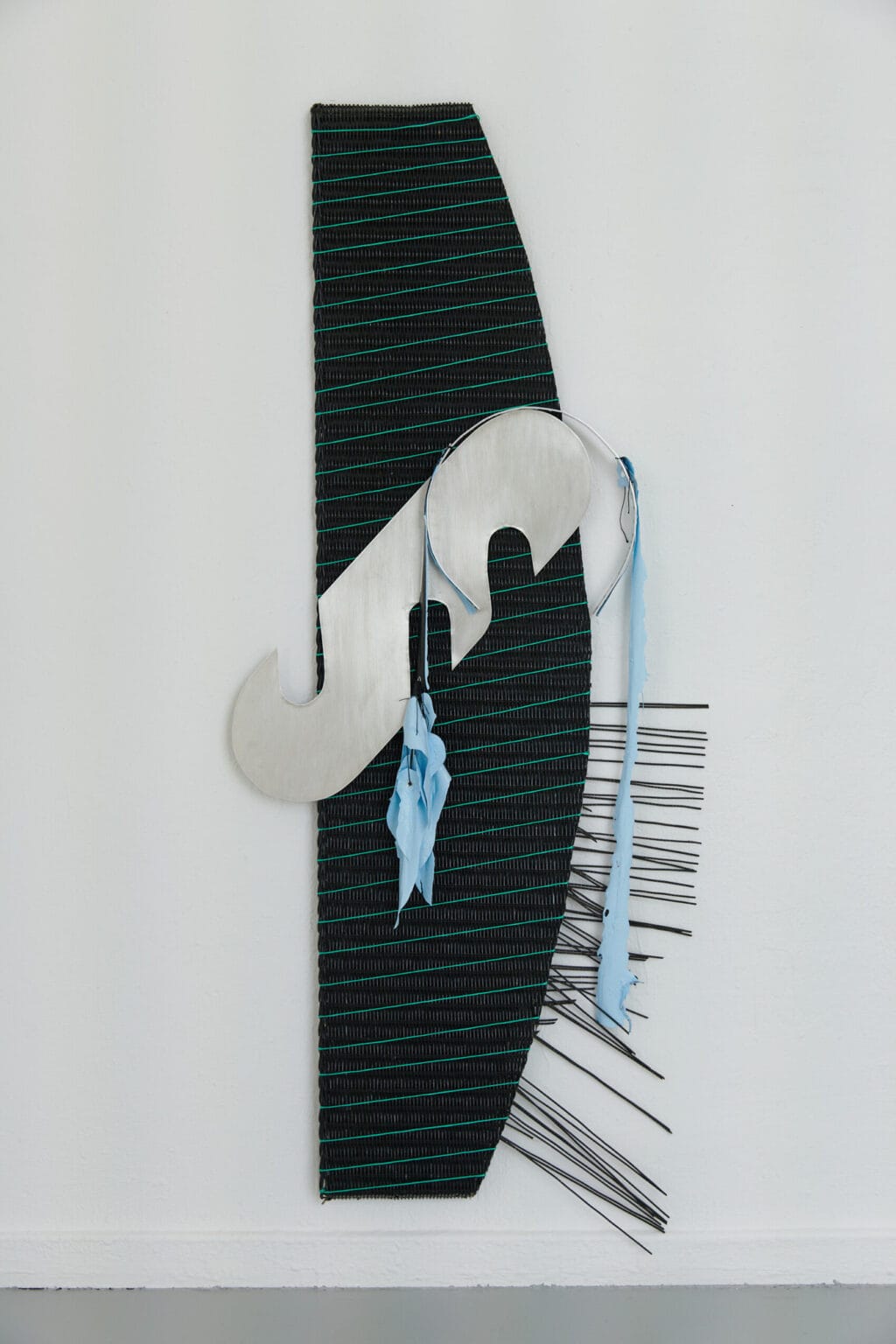 Foto: Ein Objekt, dass auf unterschiedlichen Materialien besteht, auf weißer Wand.