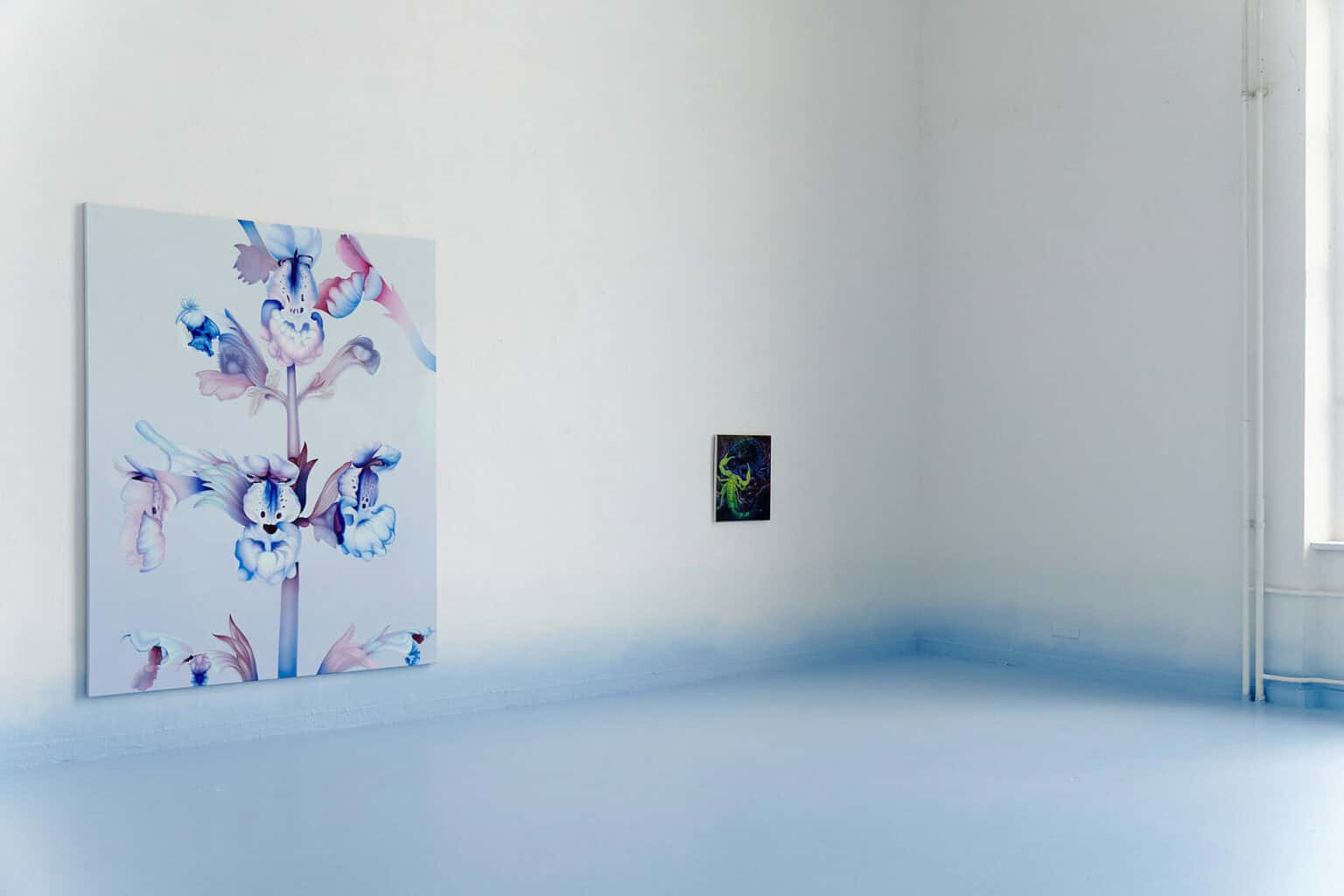 Foto: Ein Raum mit weißen Wänden und hellblauem Boden. Der untere Bereich der Wand ist ebenfalls mit hellblauer Farbe bemalt, die nach oben hin ausfaded. An der Wand hängen eine groß- und eine kleinformatige Arbeit auf Leinwand.