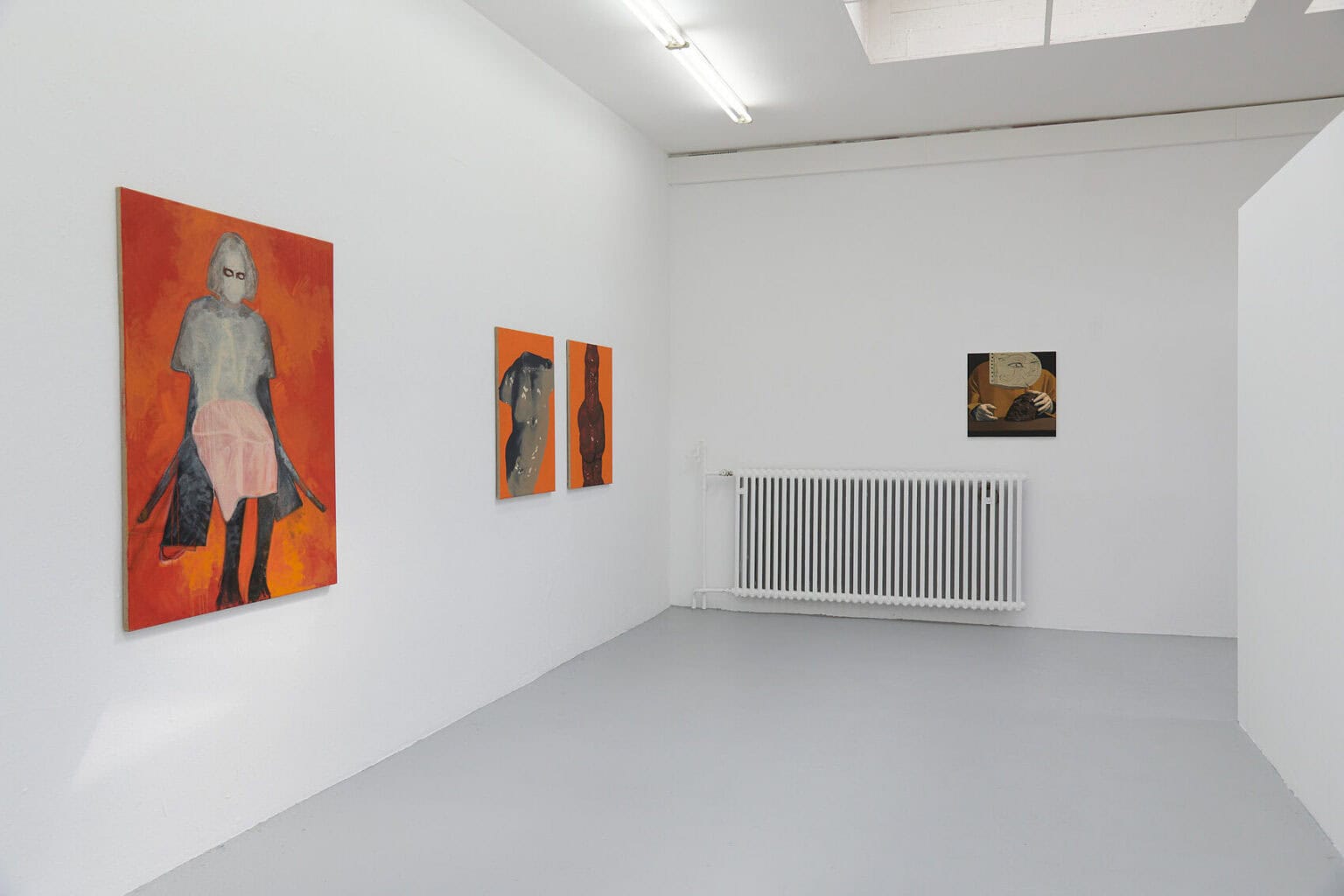 Foto: Ein Raum mit weißen Wänden und grauem Boden. An der Wand hängen Leinwände im Klein-,Mittel- und Großformat.