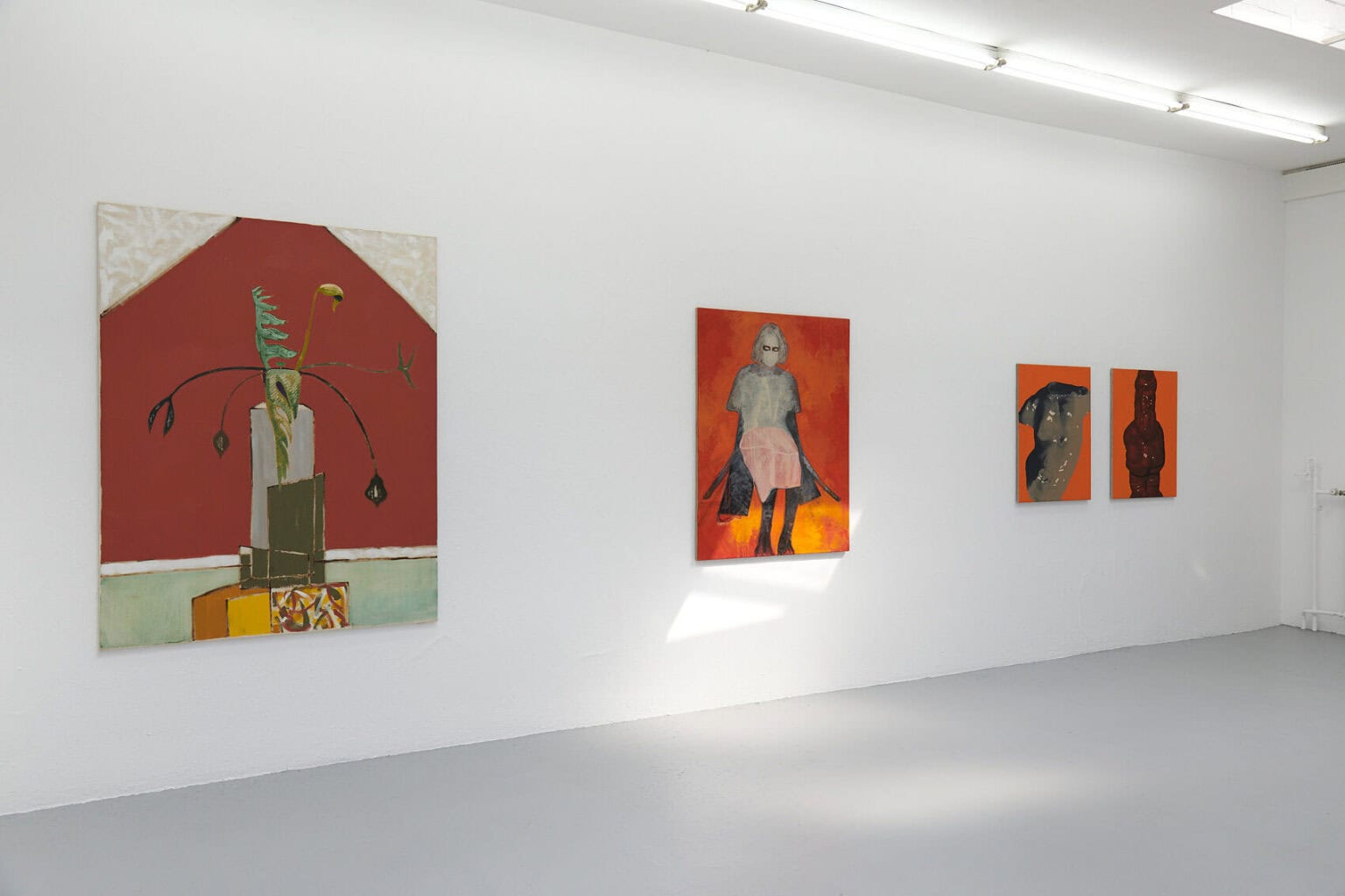 Foto: Ein Raum mit weißen Wänden und grauem Boden. An der Wand hängen Leinwände im Mittel- und Großformat.