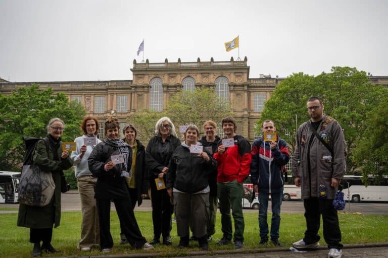Foto: Gruppenbild vor historischem Gebäude mit wehenden Fahnen
