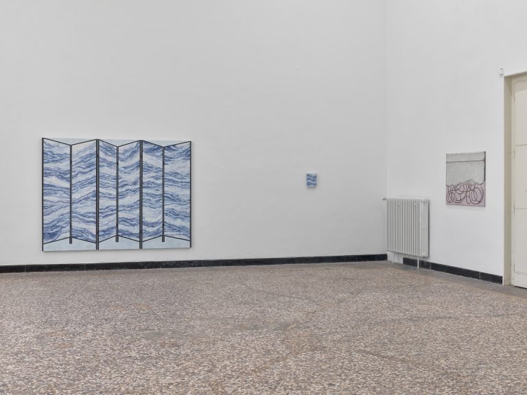 Foto: Aufnahme eines Ausstellungsraums. Rechts und links sind an den Wänden  Gemälde zu sehen.