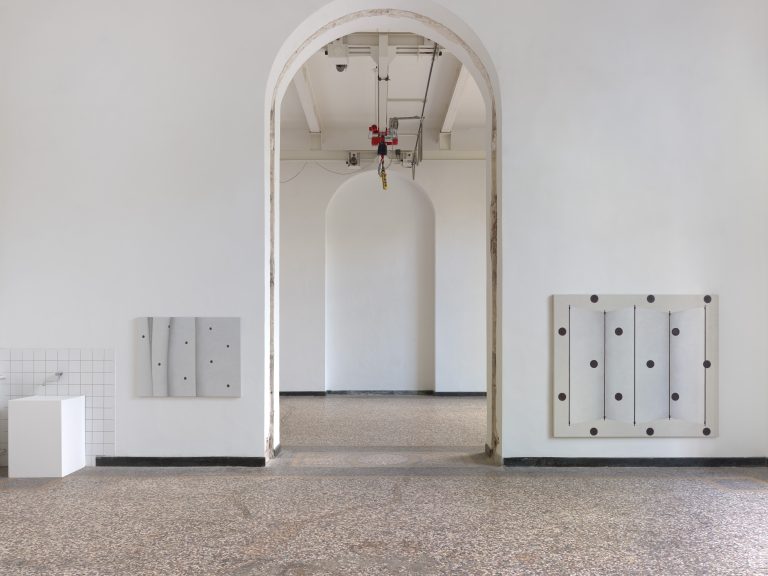 Foto: Aufnahme eines Ausstellungsraums mit Blick in den nächsten Raum durch einen großen Durchgang. Rechts und links sind an den Wänden des Durchgangs großformatige Gemälde zu sehen.
