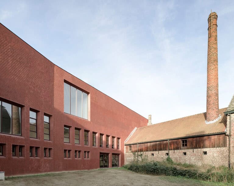 Foto: Ein großes, modernes Backsteingebäude, das an ein kleineres altes Industriegebäude angebaut ist.