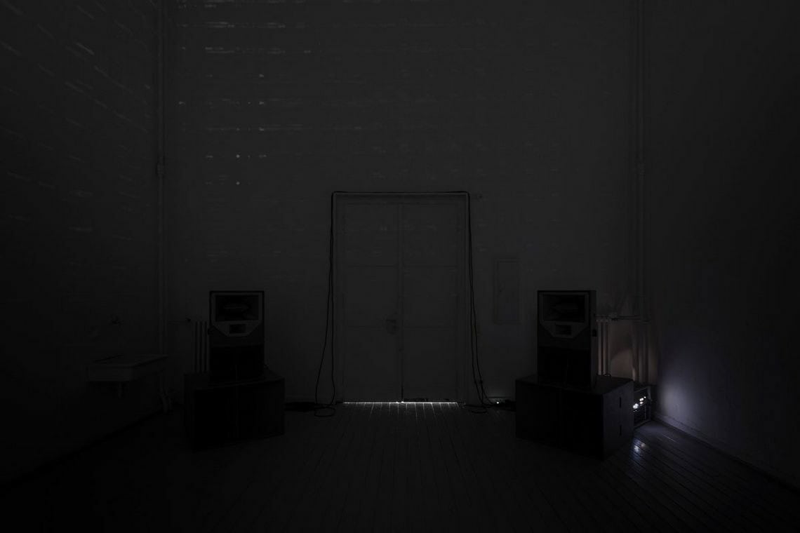 Foto: Ein abgedunkelter Raum mit Tür, in dem ein schwaches, weißliches Licht leuchtet.