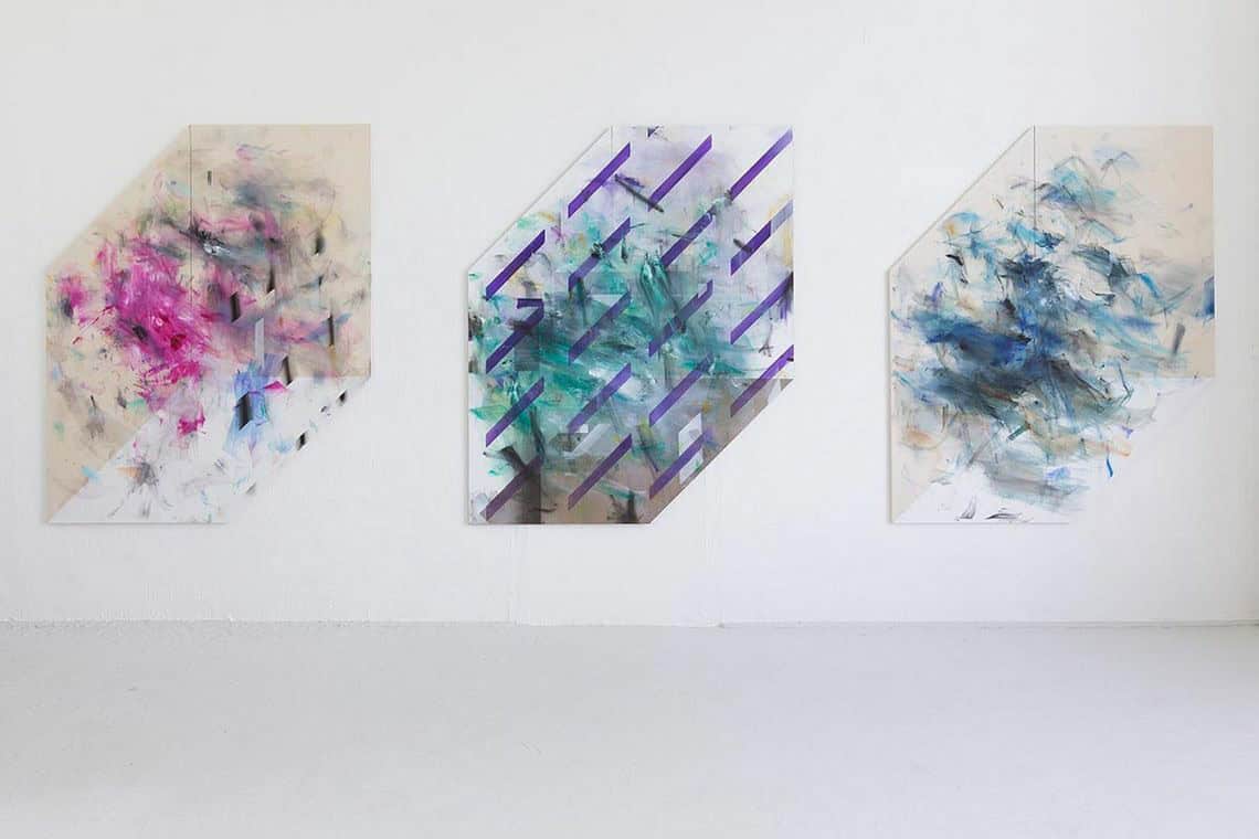 Foto: Eine weiße Wand in einem Raum mit grauem Boden. An der Wand drei bleichgroße, sechseckige Objekte, auf gleicher Linie, im gleichen Abstand zueinander.