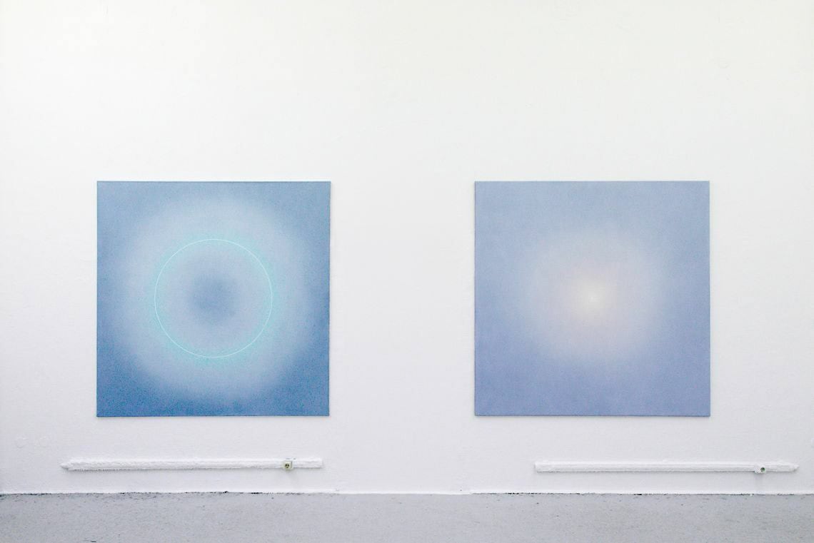 Foto :Ein Raum mit weißer Wand und grauem Dielenboden. An der Wand hängen zwei großformatige Leinwände im gleichen, quadratischen Format.