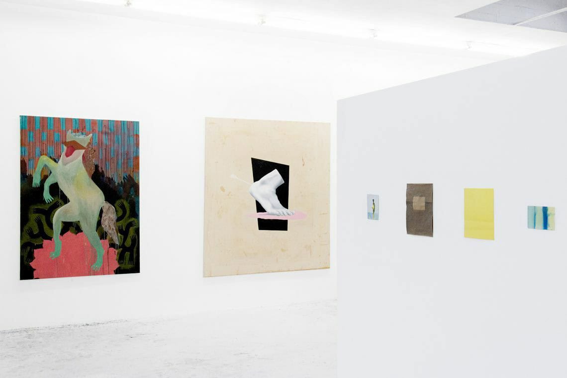 Foto: Ein Raum mit weißen Wänden und hellgrauem Boden. An den Wänden hängen zwei großformatige Leinwände und mehrere kleinformatige Papierarbeiten.