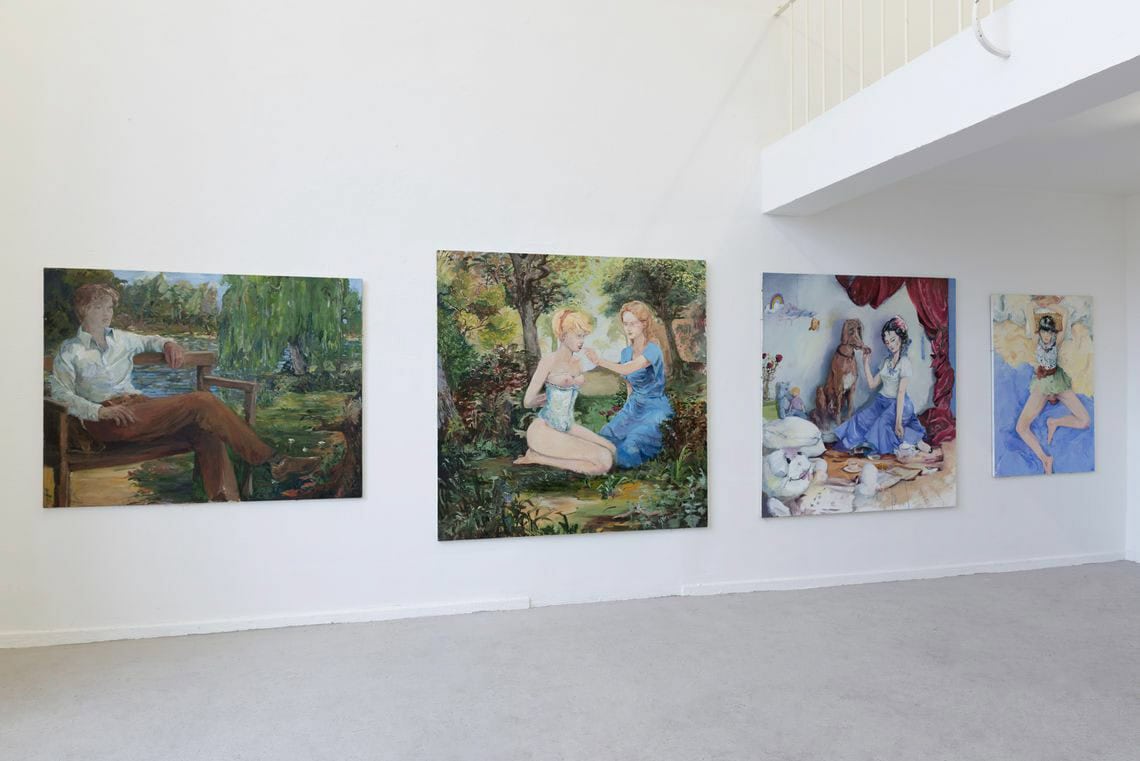 Foto: Ein Raum mit weißen Wänden und grauem Boden. An der Wand befinden sich großformatige Leinwandarbeiten, die auf ähnlicher Höhe hängen.