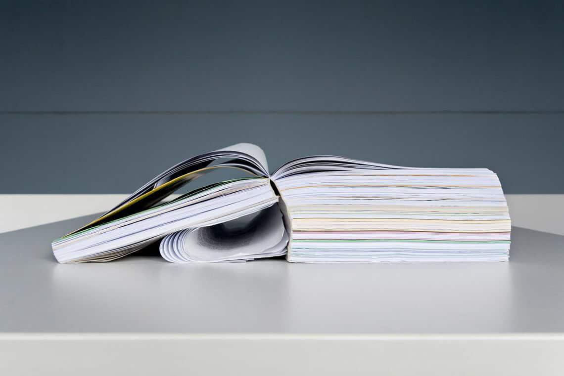 Foto: Detailaufnahme eines dicken, aufgeschlagenen Buches auf einem Tisch.